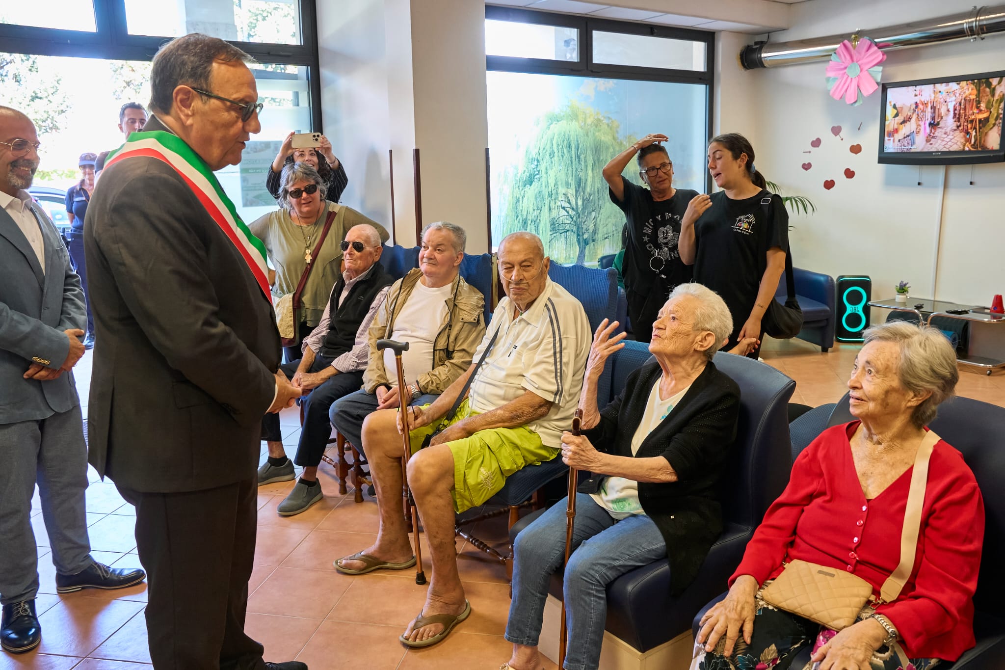 Gli ospiti seduti in sala accolgono i visitatori il giorno dell'inaugurazione